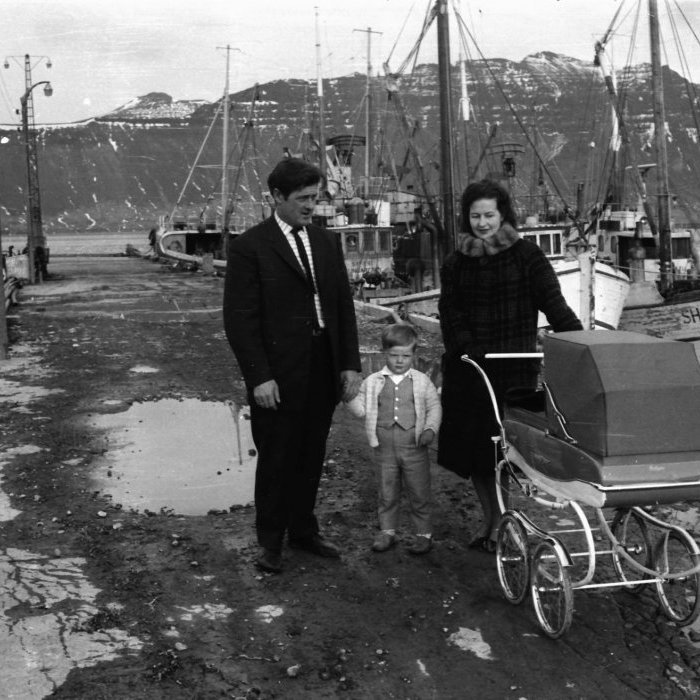 Björn Ásgeirsson skipstjóri og eiginkona hans Aðalheiður Lydía Guðmundsdóttir niðri á bryggju með börnin sín, þau Guðmund Ásgeir Björnsson og í vagninum Andreu Þórunni Björnsdóttur. Myndin er sennilega tekin vorið 1963.