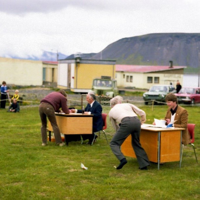 Bankavíxla boðhlaup. Hlaupið er að skrifborðum Sparisjóðs Eyrarsveitar og Samvinnubankans.                                                                                                                Við skrifborðin sitja Halldór Finnsson úr Sparisjóðnum og Garðar Eiríksson úr Samvinnubankanum. Guðbjartur Cecilsson er annar keppenda, en hver er hinn?