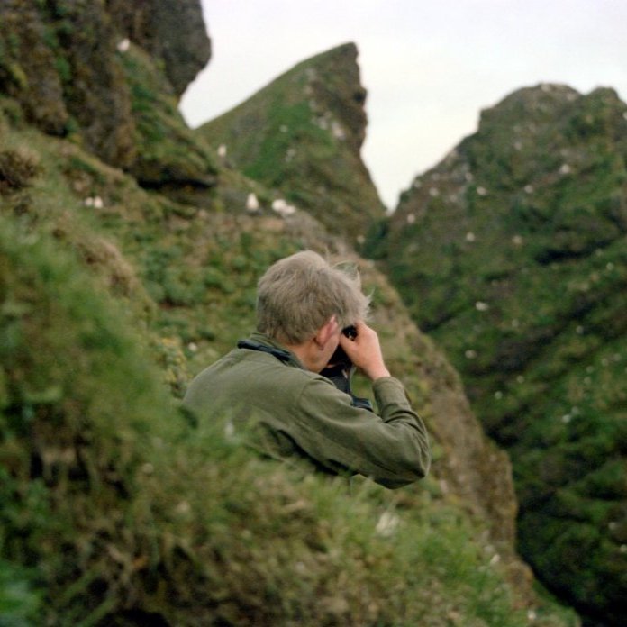 Bæring mundar myndavélina til að taka myndir af fuglum í bjarginu.