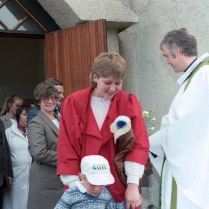 Að lokinni Sjómannadagsmessu tekur séra Jón í höndina á kirkjugestum. Fremst á myndinni er prúður og stilltur drengur með móður sinni. Talið frá vinstri, Elis Guðjónsson, okkur vantar næsta nafn, þá koma Gríma Guðmundsdóttir, Gerður Guðlaugsdóttir, Jón Snorrason, Selma Friðfinnsdóttir, Guðbjörg Jenný Ríkarðsdóttir, Garðar Hafsteinsson og séra Jón Þorsteinsson.