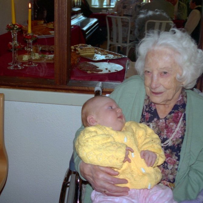 Mynd tekin á Dvalarheimilinu Fellaskjóli, Jóný Þorsteinsdóttir er hér með litla stúlku í fanginu en okkur vantar nafn hennar. Jonna var ekki óvön því að vera með lítil börn í fanginu eða á hné sér að syngja fyrir þau eða segja sögur og ævintýri.