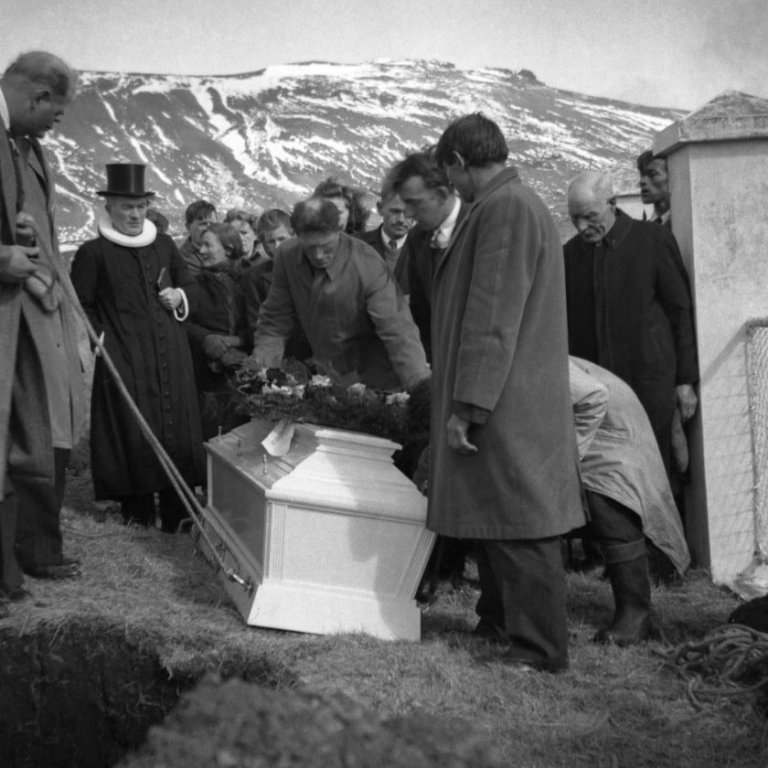 Séra Jósef Jónsson var fæddur árið 1888 og lést árið 1974. Séra Jósef var kosin prestur að Setbergi á Snæfellsnesi árið 1919 og gegndi hann því samfleytt í 35 ár til vorsins 1954, ásamt því að vera prófastur í Snæfellsness prófastsdæmi. Séra Jósef var ásamt því að vera sóknarprestur mikill bóndi, auk þess sinnti hann mikið sveitarstjórnar og félagsmálastörfum hann var t.d. oddviti Eyrsveitunga um 15 ára skeið. Eiginkona séra Jósefs var frú Hólmfríður Halldórsdóttir, Hólmfríður var einnig organisti kirkjunnar, tónmennt hennar nýttist að vonum við hin ýmsu tækifæri í sveitarfélaginu. Þau Jósef og Hólmfríður áttu fimm börn auk þess að ala upp bróðurdóttur Hólmfríðar. Sonur þeirra Pétur Jósefsson minnist á Borsalino hatt föður síns að hann hafi fengið sér nýjan hatt í Haraldarbúð og fékk þá gamli hatturinn það hlutverk að vera kríuhattur sem virðingavottur við kríurnar og til þess að verja höfuð prestsins. Þessi mynd er tekin árið 1950 við útför þar sem jarðsett er í Setbergskirkjugarði, séra Jósef stendur þarna meðal sóknabarna sinna, það væri fróðlegt að fá að vita meira um þessa athöfn og það fólk sem er á myndinni.