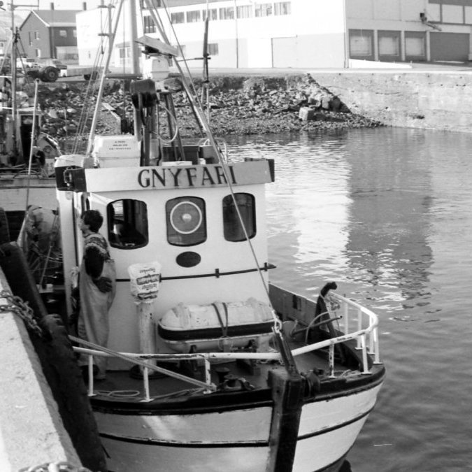 Lífið á bryggjunni, hér liggur Gnýfari SH-8 við litlu bryggju, það væri gaman að fá upplýsingar um bátinn sem liggur við bryggjuna í efsta plássinu. Á bryggjunni má þekkja Ásdísi Stefánsdóttur stiðja sig við barnavagnen um borð í Gnýfara má þekkja Smára Björgvinsson. Gnýfari var gerður út árin 1987-1988 af Elbergssonum, báturinn hét upphaflega Háborg NK 77 frá Neskaupstað,  hann var smíðaður 1976 hjá Trésmiðju Austurlands h/f á Fáskrúðsfirði.