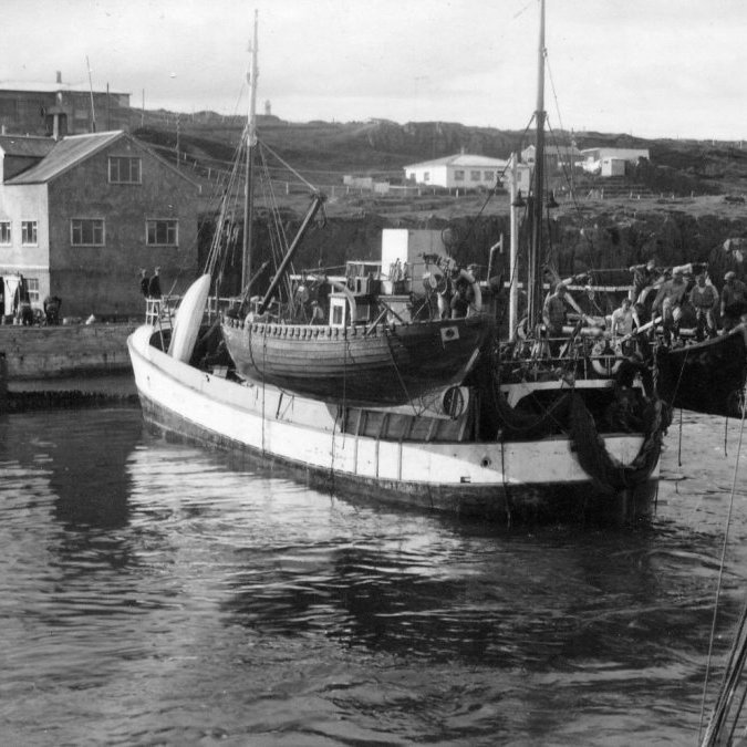 Þessi skemmtilega mynd er frá síldarárunum, líklega frá árinu 1960. Myndina tók Bæring þegar hann var vélstjóri á Grundfirðing SH-12. Okkur vantar að vita hvar þessi myndin er tekin? Hvaða síldarbátur er á myndinni? Báturinn er með skrásetningarnúmer SI og því frá Siglufirði, eftir nótabátunum að dæma þá er báturinn með stærri síldveiðibátum. Dagný SI-7 frá Siglufirði 136 brl. Smíðuð úr eik og furu svipar til þessa báts, þetta er þó ekki Dagný. Dagný og fleirri bátar af þeirri stærð sigldu með ísfisk til Englands í stríðinu. Þeir stunduðuþá einnig aðrar veiðar og flutninga, það er því líklegt að þessi bátur hafi verið einn af þeim bátum sem lögðu sig í hættu við að sigla með fisk til Englands og koma til baka heim með varning eins og t.d. kol.