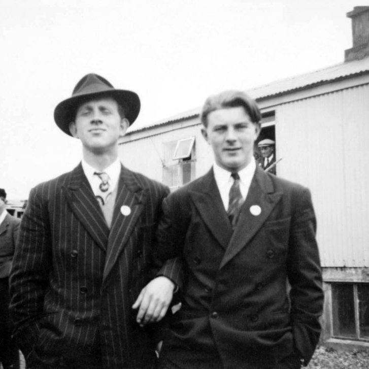 Á sjómannadegi fyrir árið 1960, þessi mynd er tekin fyrir framan Svansskála. Fremst til hægri á myndinni er Hinrik Elbergsson skipstjóri, það væri gaman að fá nöfn annara á myndinni og eins upplýsingar um barmmerkin sem mennirnir bera, eru þetta merki Sjómannadagsins? Það væri líka gaman að vita hvenær merki Sjómannadags kom til sögunnar og hvernig þau litu út.