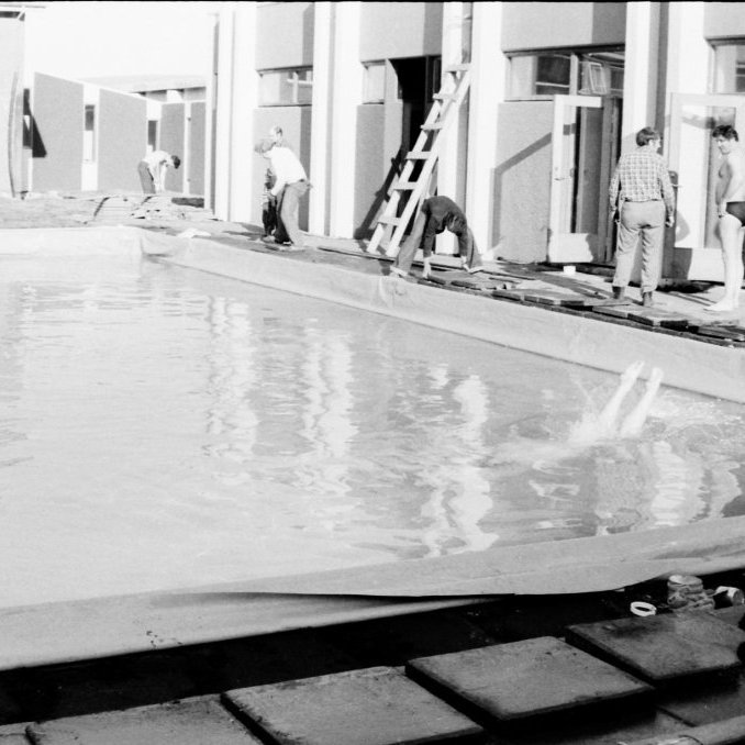 Grundfirðingar voru fullir tilhlökkunar yfir því að fá loksins sundlaug og eins og sjá má á myndini er ekkert verið að bíða eftir að laugin sé full kláruð áður en fyrsta stungan er tekin ofan í laugina. Hér er allt að gerast eins og vel má sjá.