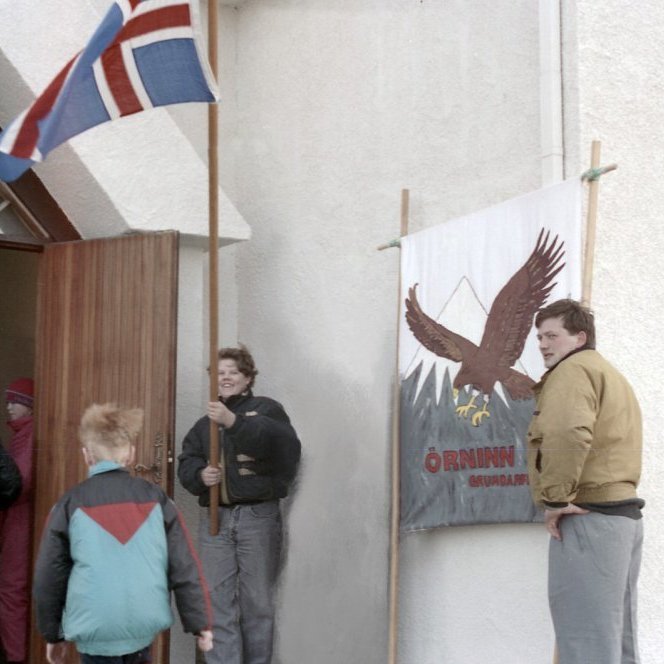 Líklega er þessi mynd tekin á 17. júní og skátarnir bjóða fólk velkomið til guðsþjónustu. Aðalsteinn Jósepsson er fánaberi og Bergur Garðarsson stendur við skátamerki Arnarins.