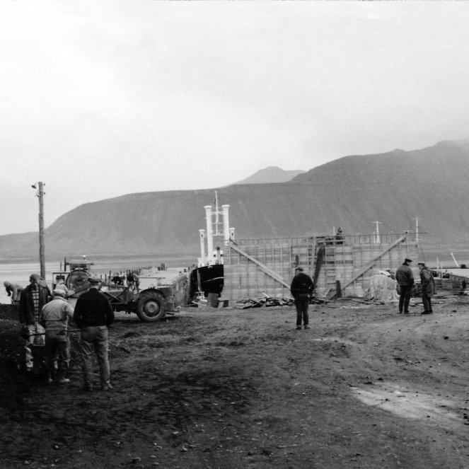 Menn við uppbyggingarvinnu árið 1966 á hafnarsvæðinu. Þarna er verið að steypa kör á milli litlu og stóru bryggju og einnig er verið að vinna við Norðurgarð (stóru bryggju). Þarna er að venju mikið fjör bæði menn að vinna og aðrir að fylgjast með. Það væri gaman að fá nöfn þeirra sem eru á myndinni.
