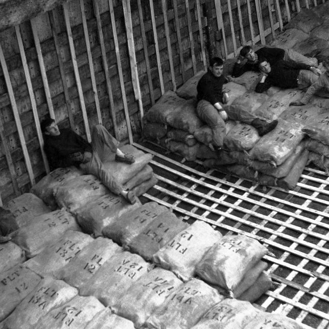 Menn í vinnu við uppskipun, stund á milli stríða. Það væri gaman á fá nöfn þeirra. Gæti verið að þarna séu talið frá vinstri Pálmi Pálsson, ?, Rögnvaldur Guðlaugsson, frændurnir Hreinn Bjarnason og Bernhard Guðnason (Benni) og svo vantar þann sem er lengst til hægri.