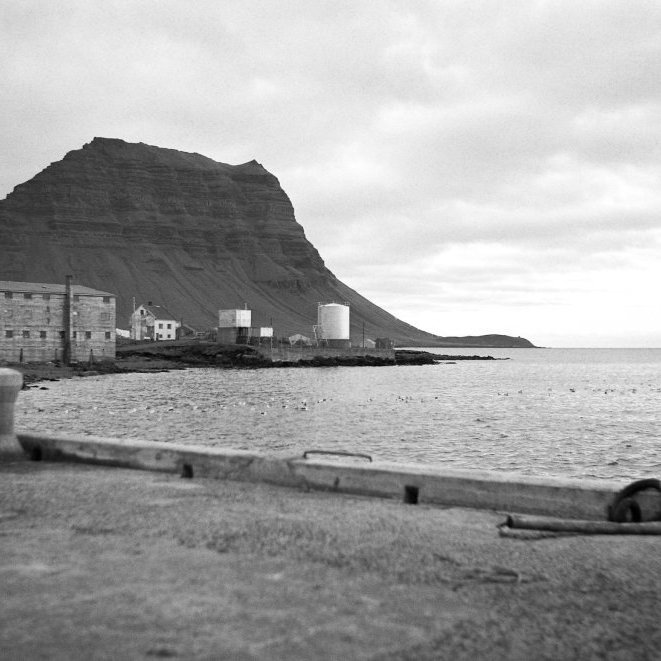 Grundarfjörður séð frá útskotinu sem var á Stóru bryggju (Norður garður) Í dag er komin landfylling sem stækkar hafnarsvæðið þónokkuð, þar sem þarna er sjór stendur núna nýtt og glæsilegt netaverkstæði G.Run. Framnes hefur tekið miklum breytingum, á myndinni lengst til vinstri eru tankar sem tilheyrðu Hraðfrystihúsi Grundarfjarðar, næst kemur hótelið eða verbúðinn sem núna er Kirkjufell Hotel, þar áður Hótel Framnes og upphaflega Hótel Fell. Á miðri mynd er húsið Sólvellir þar sem ljósmóðirinn hún Bergþóra Sigurðardóttir og eininmaður hennar Guðlaugur Rögnvaldsson bóndi á Sólvöllum. Bergþóra starfaði sem umdæmisljósmóðir í Eyrarsveit á árunum 1934 - 1943 og 1950 – 1975, eða í um 34 ár samtals. Ný gata sem liggur milli Sólvalla og Nesvegar heitir Bergþórugata til heiðurs Bergþóru ljósmóður, en norðanverður hluti Bergþórugötu er einmitt þar sem Sólvellir heimili þeirra hjóna og barna þeirra stóð, Sólvellir var eitt af fyrstu húsunum í Grafarnesi þegar þéttbýlið byrjaði að myndast og heitir nú Grundarfjarðarbær. Lengst til hægri á myndinni eru olíutankar Esso og hjallar sem væri gaman að fá fróðleik um.