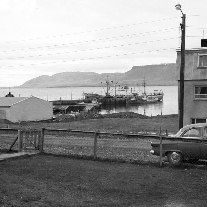 Þó nokkur breyting hefur orðið á Grundargötunni, þarna er gott útsýni á milli húsanna Grundargötu 24 (Valería) og Grundargötu 20 alla leið niður á höfn og yfir fjörðin en lóðin Grundargata 22 var aldrei byggð en var gott leiksvæði sem kallað var Bjöggatún og nær sjónum var einnig Bjöggatún. Glöggir geta örugglega komið með skýringar við myndina, t.d. hvaða bátar liggja við Stóru bryggju og hvaða skip er þarna við Stóru bryggju? Er útskipun í gangi eða uppskipun? Hvaða trillur eru niður við hjallanna og hver á þessa hjalla? Lengst til hægri á myndinni er þetta bíllin hans Benna á Berserkseyri? Til vinstri á myndinni er Fiskverkun Soffaníasar og í dag hefur húsnæði fiskverkunarinnar stækkað þannig að í dag sjáum við frá þessu sjónarhorni frá Grundargötu 19 (Snarræði) aðeins Fiskvinnslu húsið og svo skemmtilega kaffihúsið Valeríu og Grundargötu 20 sem lenti í brunatjóni.