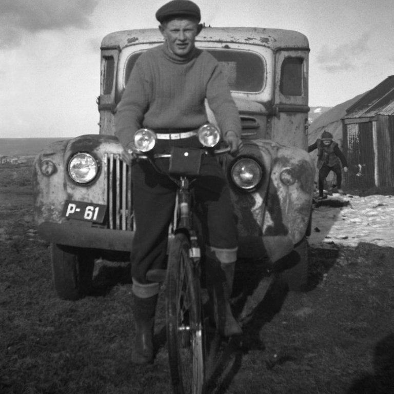 Þessi skemmtilega mynd frá Bæring er meðal þeirra elstu. Getur verið að maðurinn á hjólinu sé Jón Elbergsson? Þekkir einhver þann sem er fyrir aftan bílinn og gaman væri að fá að heyra meira um bílinn P-61 og hvar er myndin tekin?