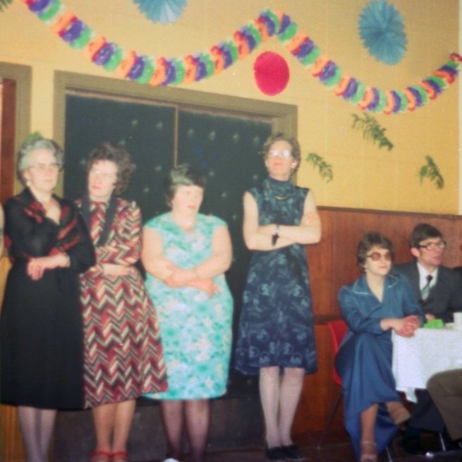 Þessi skemmtilega jólamynd er frekar óskýr en hún segir svo góða sögu um jólastemmingu frá liðinni tíð ca. 50 ár síðan Bæring tók þessa mynd í samkomuhúsinnu. Myndin sýnir hvernig samkomuhúsið var skreytt, t.d. dúkuð borð og kertaljós, einnig tísku þessa tíma í glæsilegum fatnaði. Þessar fallegu konur sem skarta fallegum kjólum eru talið frá vinstri, Rósa Sigurþórsdóttir, Pálína Gísladóttir, Margrét Erla Hallsdóttir, Auður Jónsdóttir, Jóhanna D Magnúsdóttir (Nóa) og Árdís Sveinsdóttir, herramennirnir eru þeir Kjartan Gunnarsson, Páll Torfason og Arnór Kristjánsson.