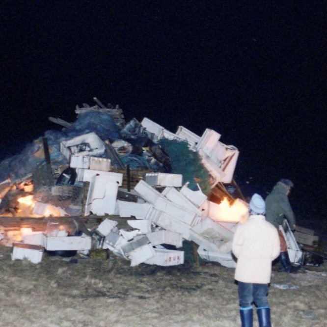 Þessi áramótabrenna sem verið er að gera klára er líklega frá árunum í kring um 1990 og mjög líklega ekki samþykkti í dag að brenna því efni sem þarna er búið að stafla upp. Þarna er Guðbjartur Cecilsson (Batti) að leggja loka hönd á brennuna sem brennustjóri, veit einhver hvar þessi brenna var staðsett og árið?