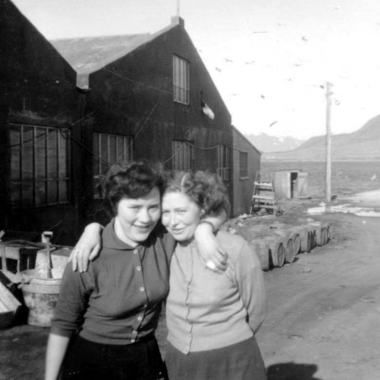 Þarna eru þær vinkonur Silla og Ragga fyrir framan Hraðfrystihúsið og eru líklega matráðskonur í Svansskála sem er þarna rétt hjá? Frá vinstri  Sigurlín Gunnarsdóttir frá Eiði og Ragnheiður Skarphéðinsdóttir frá Grund.