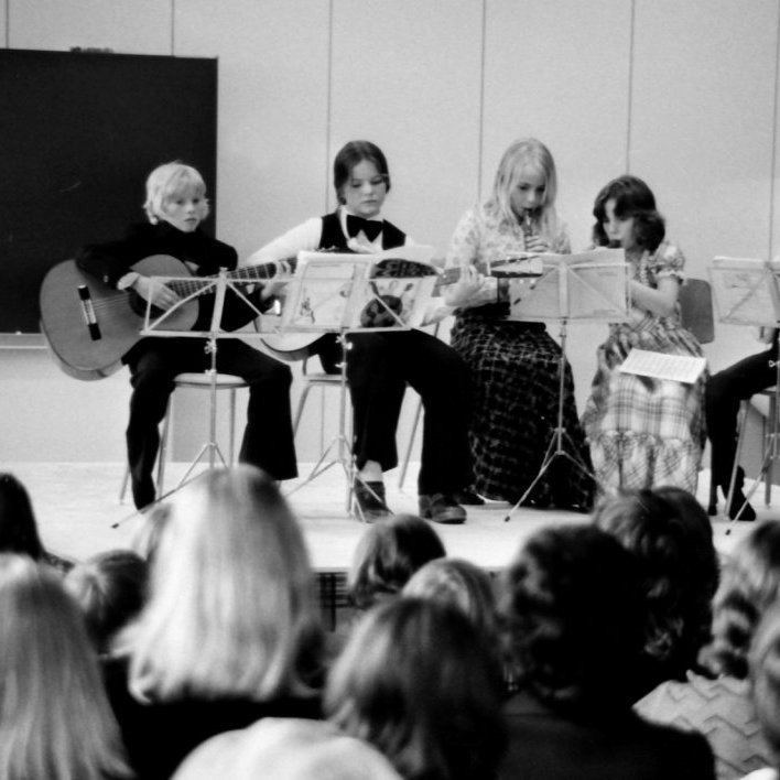 Þann 15. janúar síðastliðin átti Tónlistarskóli Grundarfjarðar 50 ára afmæli. 2025, eru 50 ár síðan Tónlistarskóli Grundarfjarðar var stofnsettur 15. Janúar árið 1975 og varð því hálfrar aldar gamall 15. Janúar 2025. ... Innritun í Tónlistarskólann hófst 9. janúar 1975 og innrituðust þann dag 114 manns, bæði börn og fullorðnir. Kennsla hófst svo miðvikudaginn 15. janúar og fór hún fram í safnaðarheimili Grundarfjarðarkirkju og í skrifstofu kirkjunnar. Í byrjun var kennt á píanó og blokkflautu. Það voru þau Kristín Jóhannesdóttir og sr. Jón Þorsteinsson sem sáu um kennsluna frá áramótum til vors. Fyrsta starfstímabili skólans lauk 3. maí með tónleikum þar sem 62 nemendur tóku þátt en 77 nemendur skildu við skólann að vori. Tónleikarnir voru haldnir í nýbyggingu barna- og miðskóla Eyrarsveitar og voru þeir vel sóttir. Hilmar Jón Hauksson hóf að starfa við tónlistarskólann haustið eftir. Hilmar var kennari við barnaskólann og kenndi hann eldri nemendum á gítar... Myndin er frá fyrstu tónleikunum þann 3. Maí árið 1975. Nemendur talið frá vinstri eru Elínborg Geirmundsdótttir á píanó, Ragnar Þór Alfreðsson gírar, Hrönn Harðardóttir gítar, síðan vantar okkur nafn, Ragnheiður Elíasdóttir og Ægir Berg Elísson