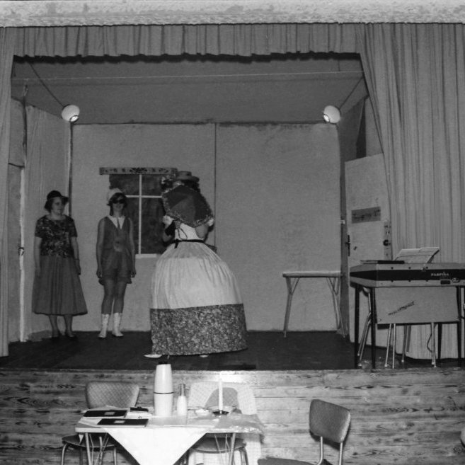 Þessi skemmtilega mynd er líklega frá aðalfundi kvenfélagsins ef horft er á borðið fyrir framan sviðið, myndin er líklega frá miðjum sjöunda áratugnum. Þarna er verið að kynna tísku og að myndinni að dæma spannar tískan yfir aldir. Lengst til vinstri á myndinni er Ólöf Pétursdóttir að kynna þátttakendur sýningarinnar, lengst til hægri sytja tvær konur og gæti önnur þeirra verið Þorbjörg Daníelsdóttir?