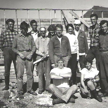 Sóknarprestur Setbergsprestakalls sr. Magnús Guðmundsson hvatti mjög til að byggð yrði ný kirkja í kauptúninu þar sem þéttbýli fór að myndast upp úr árinu 1940, sr. Magnús fór fyrir flokki fólks sem kom að kirkjubyggingunni, bæði heimafólki og öðrum. Byggingarmeistari var Guðbjartur Jónsson, Guðbjartur hélt nákvæma dagbók og skrifaði lýsingu á smíðinni og helstu viðburðum árin sem hann sá um byggingu kirkjunnar fyrir sóknarnefnd Setbergssóknar og einnig tók hann margar ljósmyndir í gegn um þessi ár. Vinna hófst 20. Júní árið 1960 en þá var þegar búið að ýta ofan af jarðvegi og sprengja. Á myndinni sjáum við fyrri vinnuflokkinn sem voru sjálfboðaliðar á vegum alkirkjuráðs bæði íslenskir og erlendir (Oikoumeniski vinnubúðaflokkur), sem komu frá ýmsum löndum Evrópu og var eitt af verkefnum alkirkjuráðs sem fór í gang eftir síðari heimsstyrjöldina í þeim tilgangi að auka samskipti milli þjóða Evrópu og vinna þannig að gagnkvæmri virðingu og friði sem og að byggja upp samfélagið sem var í rústum eftir stríð. Lengst til hægri á myndinni er sr. Magnús Guðmundsson, fjórði til vinstri er Guðbjartur Jónsson.  Grundarfjarðarkirkja var vígð 31. Júlí árið 1966.