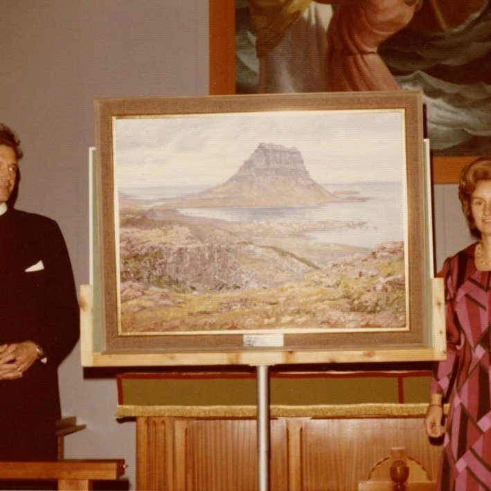 Mynd af prestshjónunum að taka við þakklætisvotti frá sóknarbörnum sínum þegar komið er að kveðjustund. Gjöfin er fallegt olíumálverk eftir Ragnar Pál Einarsson listmálara og gítarleikara frá Siglufirði.