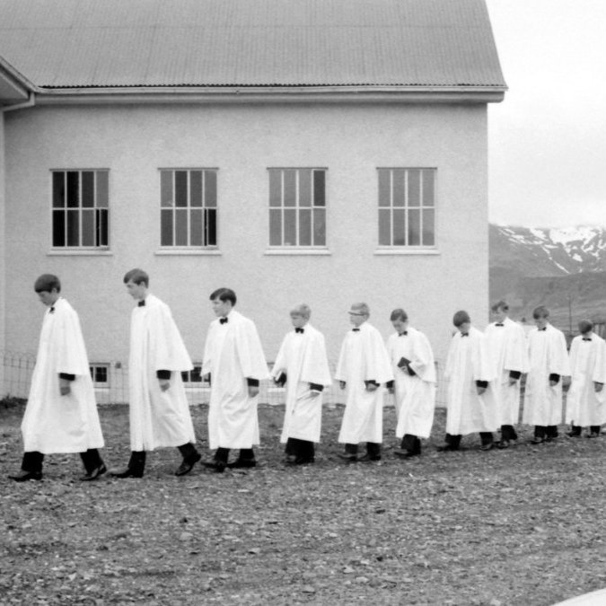 Á þessari mynd gengur fríður hópur fermingarbarna til kirkju ásamt prestinum sínum. Árið er 1969 verið er að ferma börn fædd árið 1955. Talið frá vinstri séra Magnús Guðmundsson, Benidikt Viggó Högnason, Guðlaugur Þór Pálsson, Gunnar Hjálmarsson, Gústag Þorsteinsson, Helgi Sigurðsson, Ingi Hans Jónsson, Ingi Þór Guðmundsson, Jónas Þorkell Þorvaldsson, Ómar Elisson, Páll Guðfinnur Elíasson, Sigurrós Erna Eyjólfsdóttir, Sigríður Ingibjörg Gísladóttir, Lilja Sigurdís Sigurðardóttir.