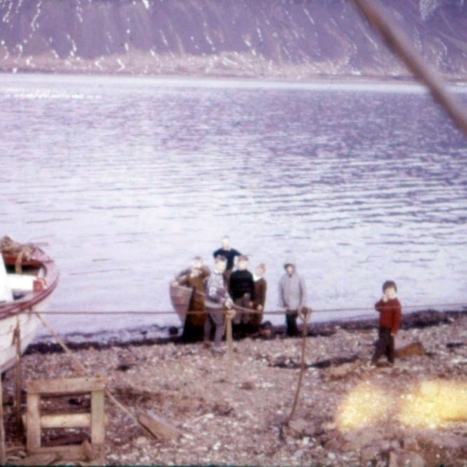 Börn, bátar og fjaran þetta hefur verið leiksvæði barna í sjávarþorpum og undirbúningur fyrir líf og störf. Gaman væri að fá nöfnin á krökkunum og bátunum sem sjást á myndinni. Bátur á firðinum, trilla í legustæðinu sínu og árabáturinn sem krakkarnir hafa mikinn áhuga á.