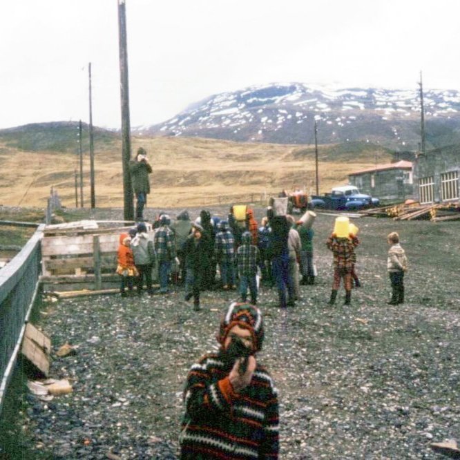 Vorboðar Sjöunda áratugsins voru krakkarnir í þorpinu með skúringarfötur, steypufötur og önnur ílát. Það væri gaman að fá nöfn á krökkunum og ljósmyndaranum sem er þarna líka að mynda krakkana. Örlítil lýsing á umhverfinu og það væri einnig gaman ef einhver gæti bætt við þær lýsingar eða sögur frá þessu vorverki grundfirskra barna. Efst til vinstri er Grunnskólinn en hann var vígður 6. janúar 1962, fyrir neðan sést girðingin hjá Gísla og Gróu en þetta voru skemmtulegustu girðingarnar að labba eftir, timburverkið við girðinguna notaði Gísli sem stíu á vörubílspallinn sinn þegar verið var að flytja kindur og á milli fengu krakkarnir að smíða út timbrinu. Efst til hægri á myndinni eru Fögruvellir þeirra Ingjalds og Guðrúnar og þar fyrir neðan verkstæðið hans Bærings þar sem nú er Ráðhús Grundarfjarðar, en lengi vel var sú bygging bara á einni hæð. Sveitarfélagið keypti það hús og byggði hæð ofan á - byggingin var vígð sumarið 2001. Á neðri hæð var slökkvistöð komið fyrir og áhaldahúsi, en á efri hæð bókasafnið og fjarnámsaðstaða - þar er nú ráðhúsið.