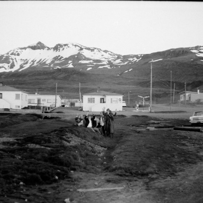 Það væri gaman ef einhver þekkti þessa hressu unglinga, en annars er gaman að sjá breytingarnar sem hafa orðið í þorpinu frá þessum tíma. Þarna er verið að ganga frá, ræsa fram og lagfæra svæðið þar sem nú er græna svæðið við heilsugæsluna. Ef vel er að gáð sést ræsið sem lá undir Grundargötu og var virkilega gaman að vaða þar í læknum sem þar rann. Enn skemmtilegra var að fara inn í stokkinn sem sést fyrir ofan Grundargötu og lá alla leið upp á Hamrahlíð. Húsið á miðri myndinni er Ragga sjoppa og beint á móti er Emil Magnússon að byggja verslunina Grund og þar fyrir ofan eru Jón Hansson og Munda byrjuð að byggja húsið sitt á Hrannarstíg 8.