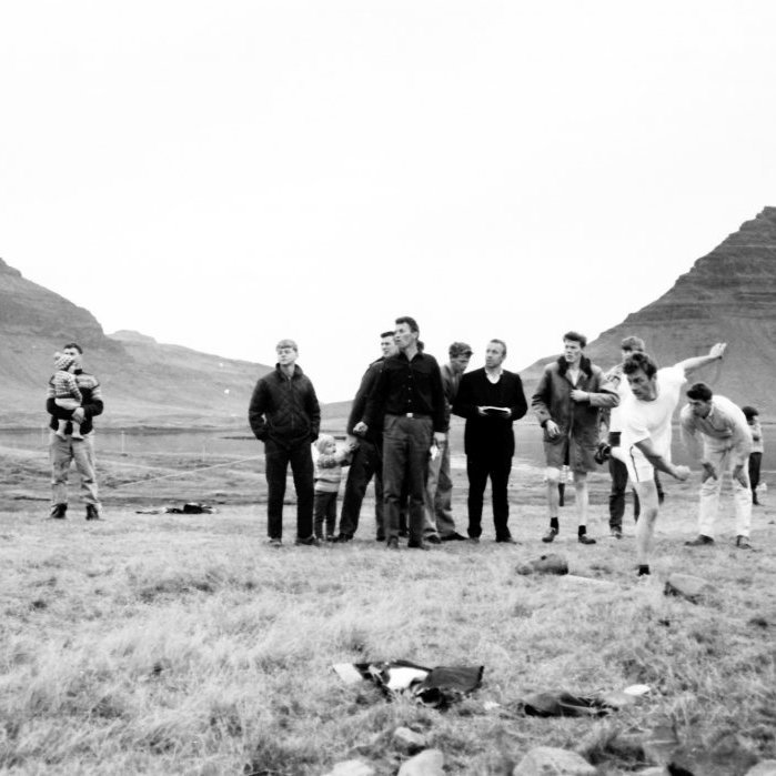 Myndin er frá Steinþórsmóti sennilega árið 1966. Í baksýn er Kirkjufell og Mýrarhyrna. Byggðin hefur vaxið mikið síðan þessi mynd var tekin, bæði hús og götur. Þar sem fólkið stendur eru sennilega húsin á Eyrarvegi, Fagurhólstúni og Fagurhól, í baksýn er Hjaltalínsholt og nýjasta byggðin í Grundarfirði. Talið frá vinstri: Þórólfur Guðjónsson með son sinn, Guðmundur Guðmundsson, maðurinn sem leiðir barnið gæti verið Hinrik Elbergsson? Fyrir framan hann er Kristján Torfason, maðurinn með bókina er Magnús Álfsson, fyrir aftan hann Grímur Haraldsson? Síðan Ívar Árnason. Sá sem kastar kúlunni er Vilberg Guðjónsson og fyrir aftan hann Ragnar Elbergsson.