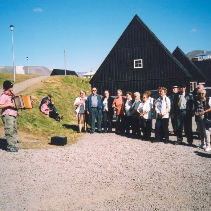 Frá ferðalagi eldriborgara, Friðjón Hallgrímsson spilar á harmonikkuna og félagar taka undir og syngja með. Í brekkunni sitja þau hjónin Kristján Torfason og Vigdís Gunnardóttir, síðan talið frá vinstri eru Eygló Guðmundsdóttir, Magnús Álfsson, Aðalheiður Magnúsdóttir, Guðný Sigurðardóttir, Guðmunda Hjartardóttir, Bára Pétursdóttir, Ólöf Pétursdóttir, Marta Böðvarsdóttir, Ragnar Kristjánsson, Gunnar Magnússon, Gísli Kristjánsdóttir, Lilja Finnbogadóttir, Jensína Guðmundsdóttir, Guðni Gústafsson, Jónína Kristjánsdóttir, Hulda Valdimarsdóttir og Elís Gíslason, ef einhver þekkir þá sem standa aftast væri gaman að fá nöfn þeirra.