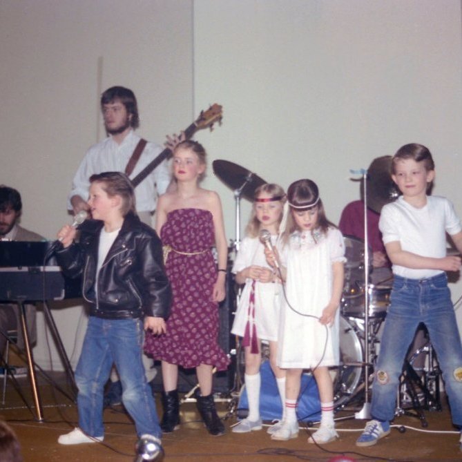 Hátíð í samkomuhúsi Grundarfjarðar árið 1982. Þarna er örugglega verið að taka atriði úr söngleiknum Grease.                                                                                                                              Þorgerður Sólveig Jónsdóttir og Sigríður Rut Júlíusdóttir söngkonur í hvítum kjólum, Ásdís Emelía Gunnlaugsdóttir t.v. í dökkum kjól, Jón Guðnason t.h. í bláum gallabuxum. Okkur vantar upplýsingar um söngvarann og hljómsveitina.